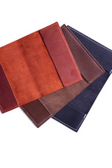 Three handmade leather passport covers isolated on white background. Closeup view. Covers are dark blue, red, brown and opened.