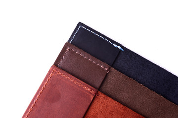 Three handmade leather passport covers stack isolated on white background. Closeup view. Covers are dark blue, red, brown and opened.