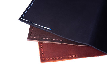 A parts of three handmade leather passport covers isolated on white background. Closeup view. Covers are dark blue, red and brown.