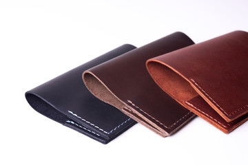 Three handmade leather passport covers isolated on white background. Covers are closed. Closeup view. Covers are dark blue, red and brown.