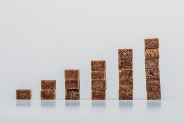 stacks of brown sugar cubes on grey background with copy space