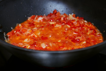 red sauce of vegetables in a deep black frying pan. Close-up