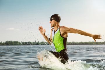 Professional triathlete swimming in river's open water. Man wearing swim equipment practicing...