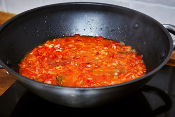 black wok with vegetable sauce on the stove. Close-up