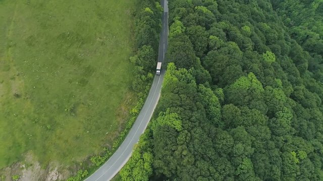 Drone view of white truck turns right on mountain road. Drone 4k, auto follow