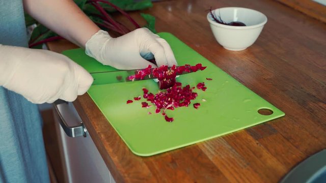 View of female hands in gloves cutting baby beets on wooden table