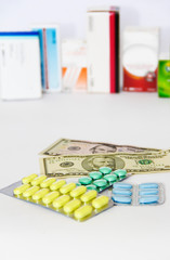 yellow green blue medical pills and american dollars on white background