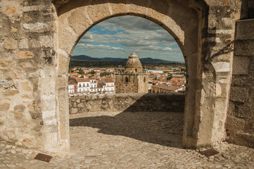 Tower with old buildings seen through arched stone gateway at Trujillo