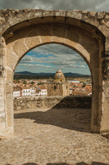 Tower with old buildings seen through arched stone gateway at Trujillo