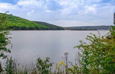 Huge sheer stone cliffs on the background of a river Dniester and a blue sky with clouds