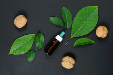Natural Serums. Cosmetic and medicinal oil of walnut on black background. Flat lay, top view, copy space
