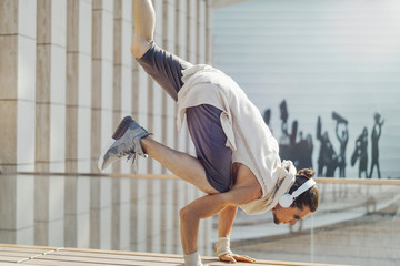 Attractive athletic man practicing yoga with maces outdoors in modern park.