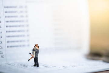 Miniature people: Small couple figures in love standing on bank passbook. Love and Valentine's day...