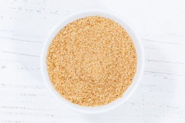 Brown cane sugar from above bowl wooden board