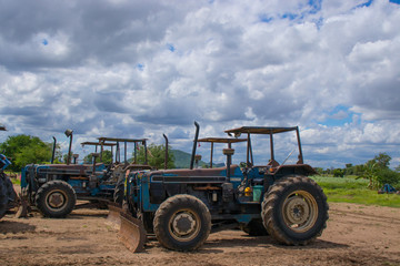 Many tractors that are parked on the farm while not in use In the morning of the farm where the clouds were gathered before forming a rainstorm