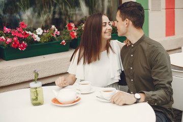 Cute couple in a city. Lady in a white dress. Pair sitting on a cafe