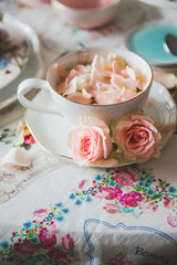 A close up of a cup with tea decorated with roses stands on a served table