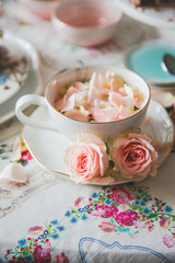 A close up of a cup with tea decorated with roses stands on a served table