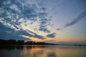 Fototapeta na wymiar Beautiful sunset over the White River with clouds reflected in the water. Bashkiria, Russia