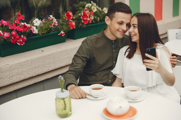 Cute couple in a city. Lady in a white dress. Pair sitting on a cafe