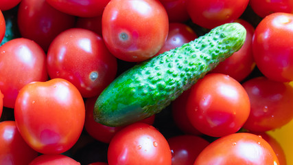 A lot of red tomato and green cucumber lying in the center.