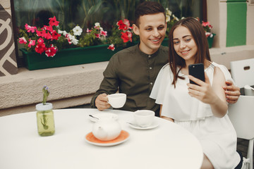 Cute couple in a city. Lady in a white dress. Pair sitting on a cafe