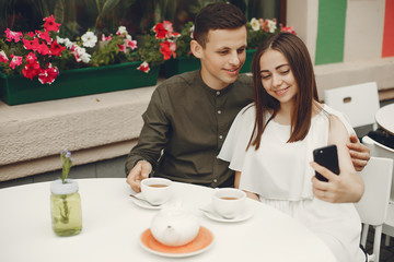 Cute couple in a city. Lady in a white dress. Pair sitting on a cafe