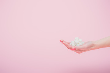 cropped view woman with handful of white sugar cubes on isolated on pink