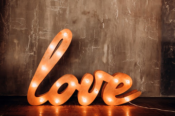 Word of Love. letters with flashlights. The bright word Love in the interior. Huge letters with light bulbs standon the floor.