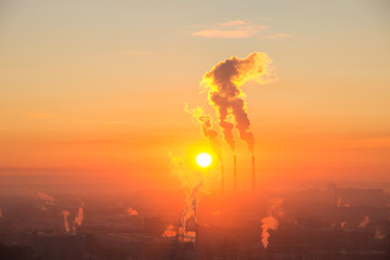 Red sun rise up on the horizon over industrial town. Smoke coming from the thermal power plant...