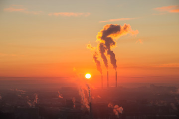 Red sun rise up on the horizon over industrial town. Smoke coming from the thermal power plant pipes. Aerial shot of sunrise over industrial zone in the city