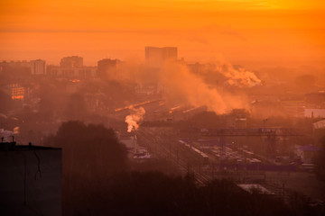 Sunrise over railway at the industrial area. Traffic jam on the bridge. Yellow sun rays comes through morning fog and dust. Containers with goods at the freight depot.Start of busy woking day