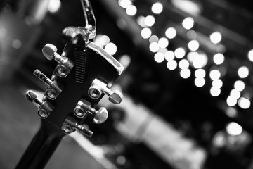 Concert flair: Close up of guitar neck, empty seats and lights in the blurry background