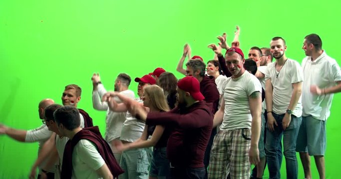 GREEN SCREEN CHROMA KEY 3/4 view group of people fans wearing red clothes doing a wave during a sport event. 4K UHD ProRes 422 HQ