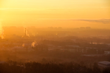 Sunrise over factory at the industrial area. Orange light rays comes through morning fog and smoke from pipes. Power plant