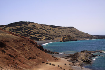 View on secluded lagoon surrounded by impressive rugged weathered cliffs in different colors - El Golfo, Lanzarote