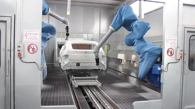  The robot paints the car body on the assembly line of the automobile plant in white.