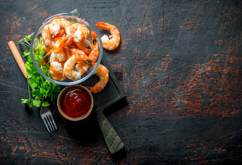 Shrimps in a bowl on a cutting Board with parsley and tomato sauce.