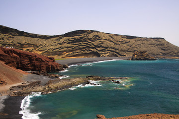 View on secluded lagoon surrounded by impressive rugged weathered cliffs in different colors - El Golfo, Lanzarote