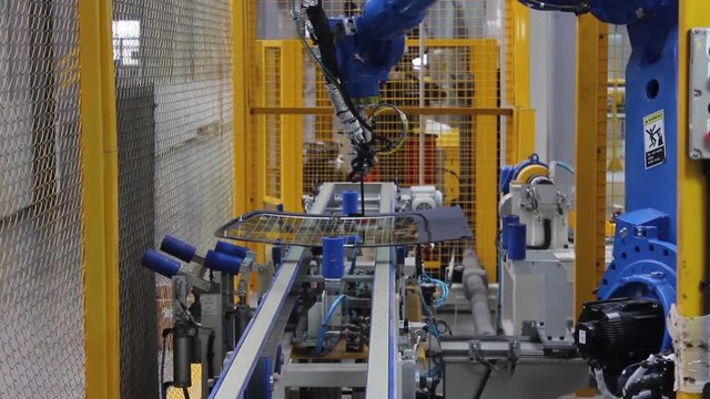 The robot, on the assembly line of the automobile plant, applies glue to the automotive glass.