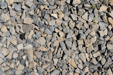 The texture of stone gravel gray. Stone rubble gray poured pile close-up. Stone path with grass.