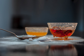 Baking soda face mask in a glass bowl on wooden surface along with baking soda powder and honey for...
