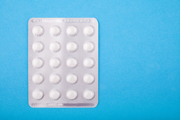 White pills in blister on an blue background. The concept of antidepressants and healing