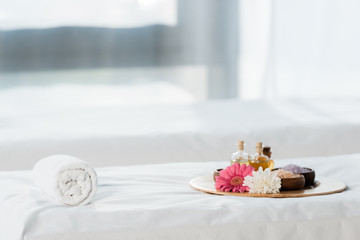 selective focus of tray with bottles of oil, bowls with sea salt and flowers in spa center