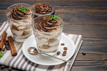 Classic tiramisu dessert in a glass on wooden background