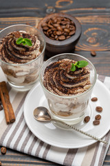Classic tiramisu dessert in a glass on wooden background