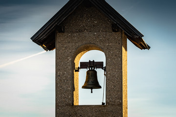 close up of beautiful old campanile, chapel tower bell in sunset, in blue sky in dolomites, italy