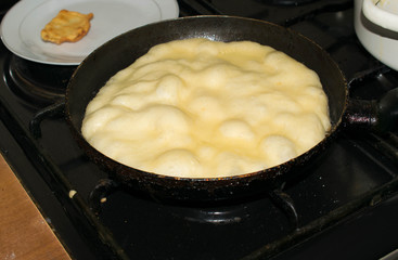 Dough in a pan unrolled with a rolling pin into a round thin cake to cook fry in hot oil a flat cake for design
