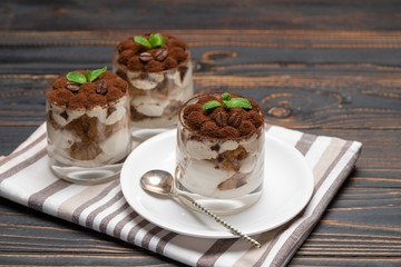 Classic tiramisu dessert in a glass on wooden background