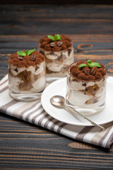 Classic tiramisu dessert in a glass on wooden background